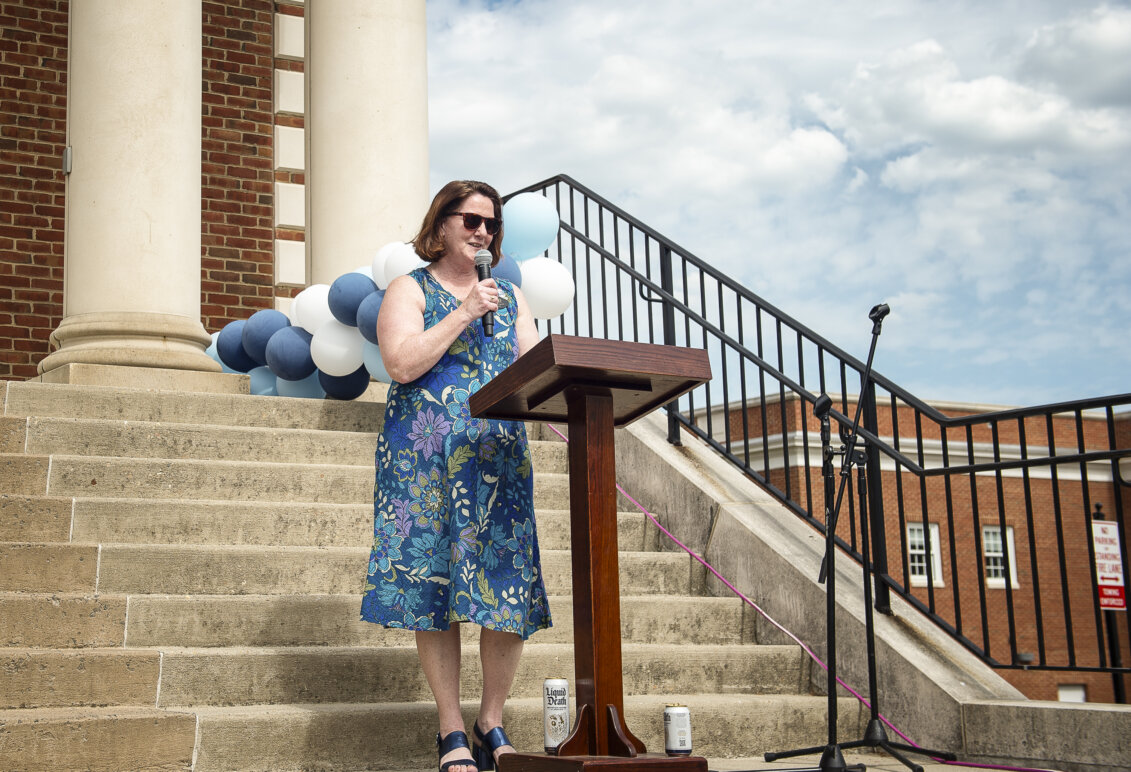 A woman speaks into a microphone in front of a crowd