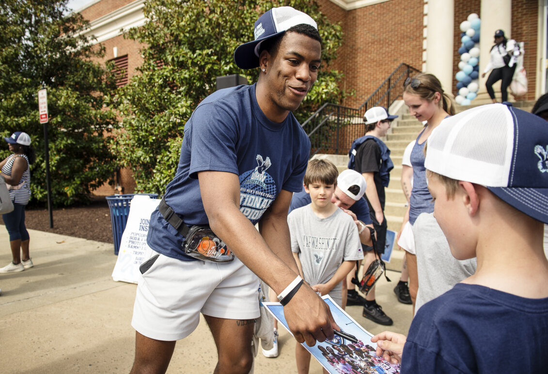 A basketball player signs an autograph for a child