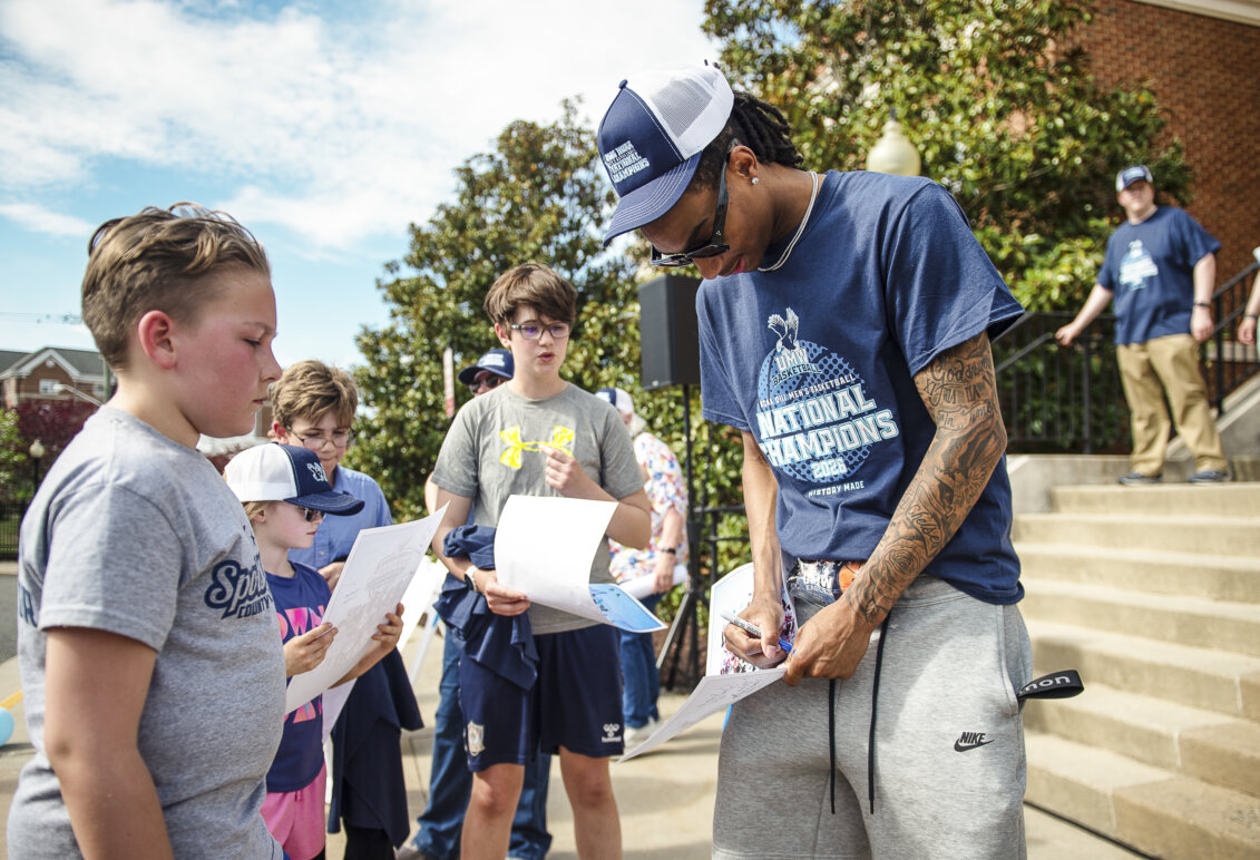 A basketball player signs an autograph for a child