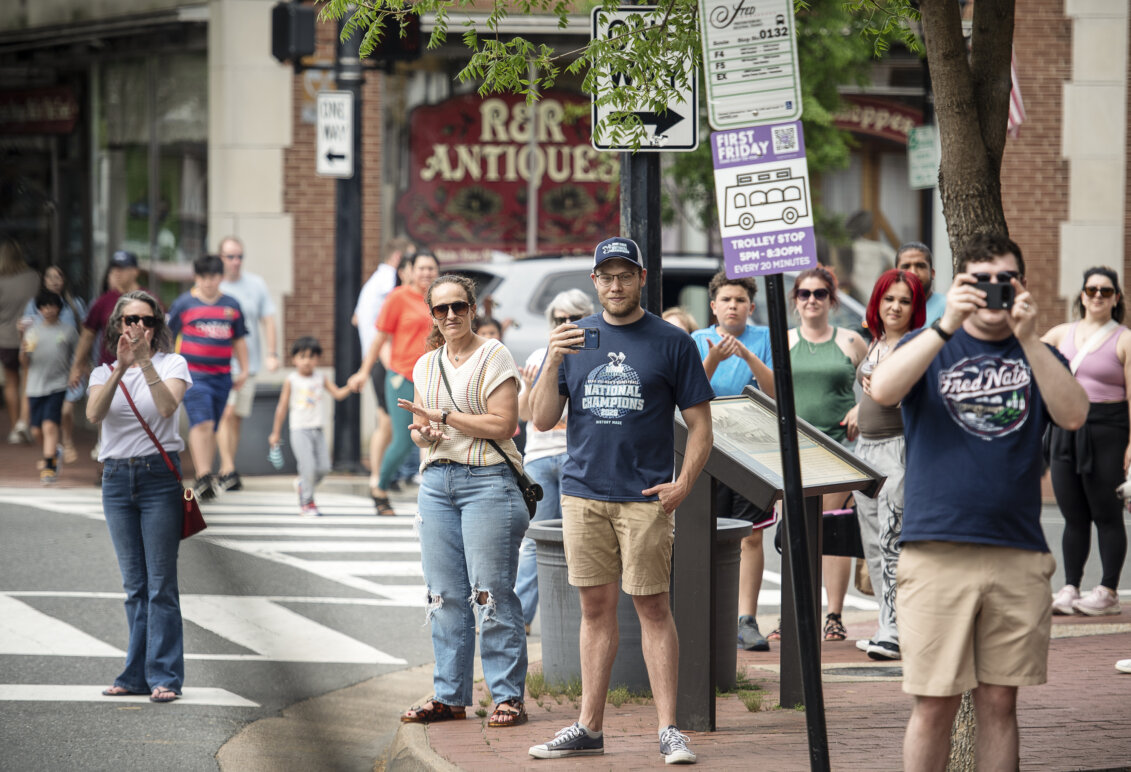 People on a city street take pictures and clap