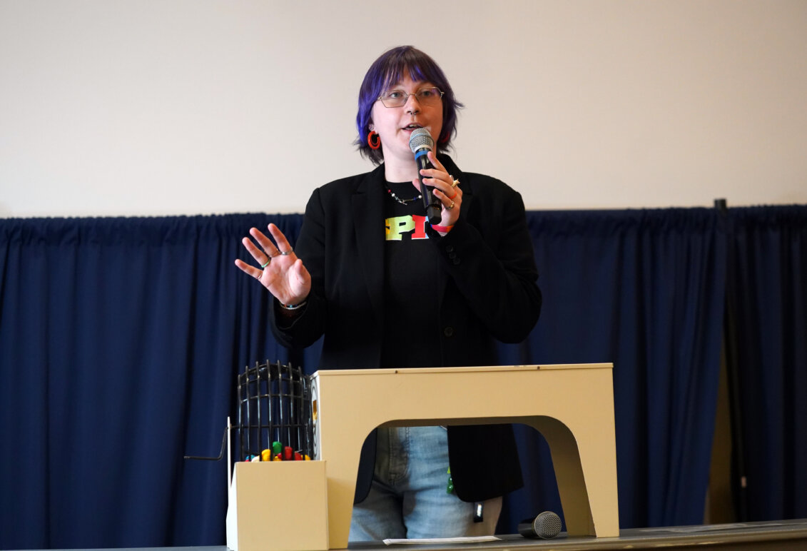 A student stands with a microphone calling Bingo numbers