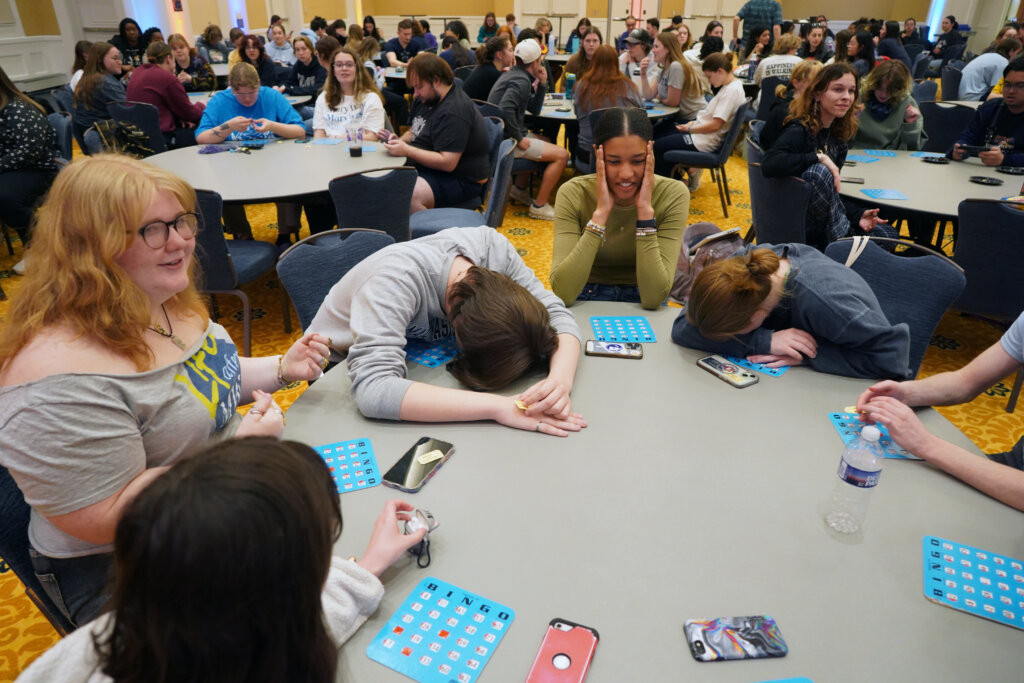 Students sit around a table playing Bingo