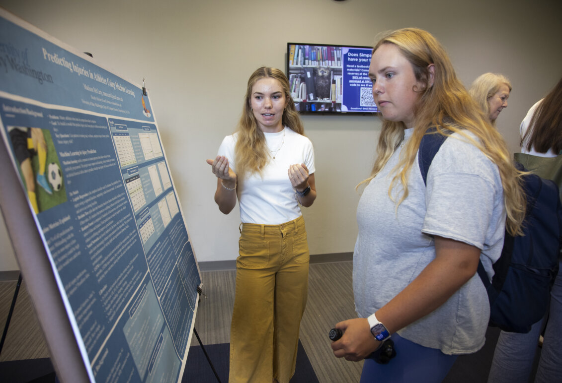 UMW student Madison McCarty standing in front of her poster with another student
