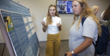 UMW student Madison McCarty standing in front of her poster with another student
