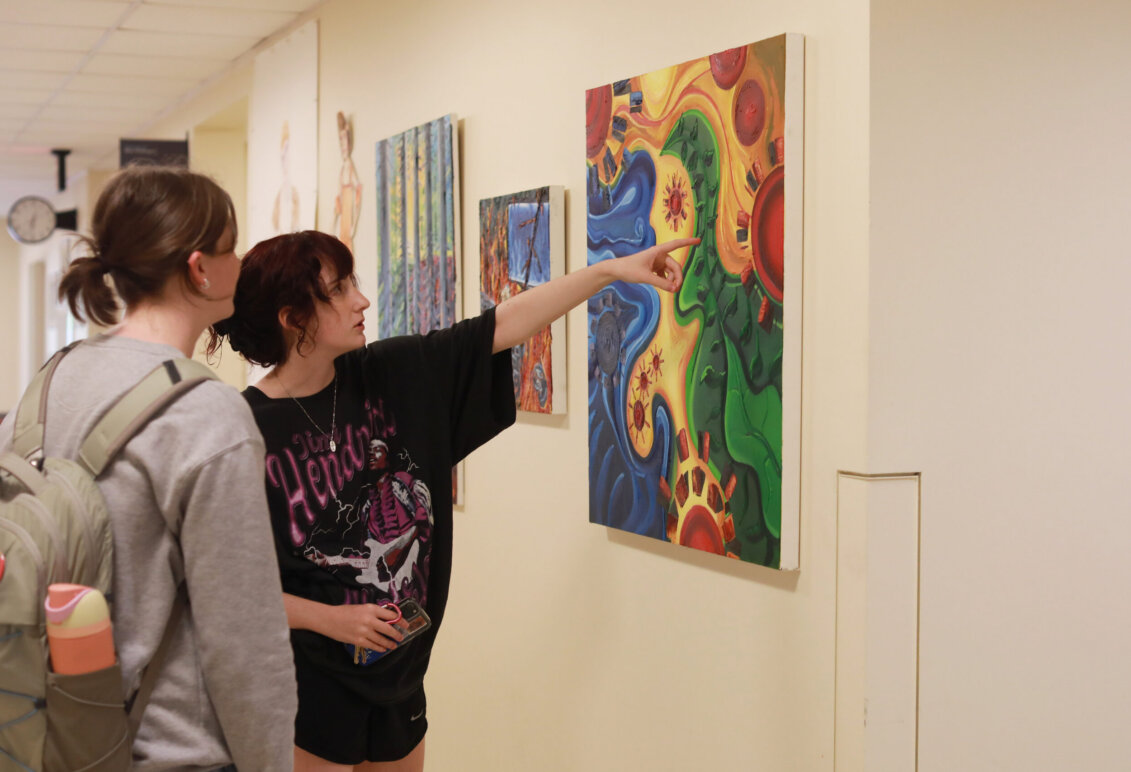 two students admire artwork on the wall on campus