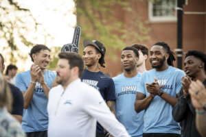 Photo of players at the event standing with a coach on stage at the event