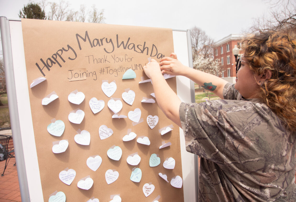 Students stick messages on a board that says Happy Mary Wash Day.