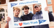 Three students in front of the Cedric Rucker University Center holding up a frame that reads #MaryWashDay and We love Mary Wash.