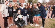 A group of UMW women's lacrosse players holding a pie. One is wearing a plastic bag and has just been pied in the face.