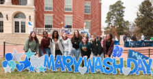 A group of students standing behind the Mary Wash Day sign in front of the Cedric Rucker University Center.
