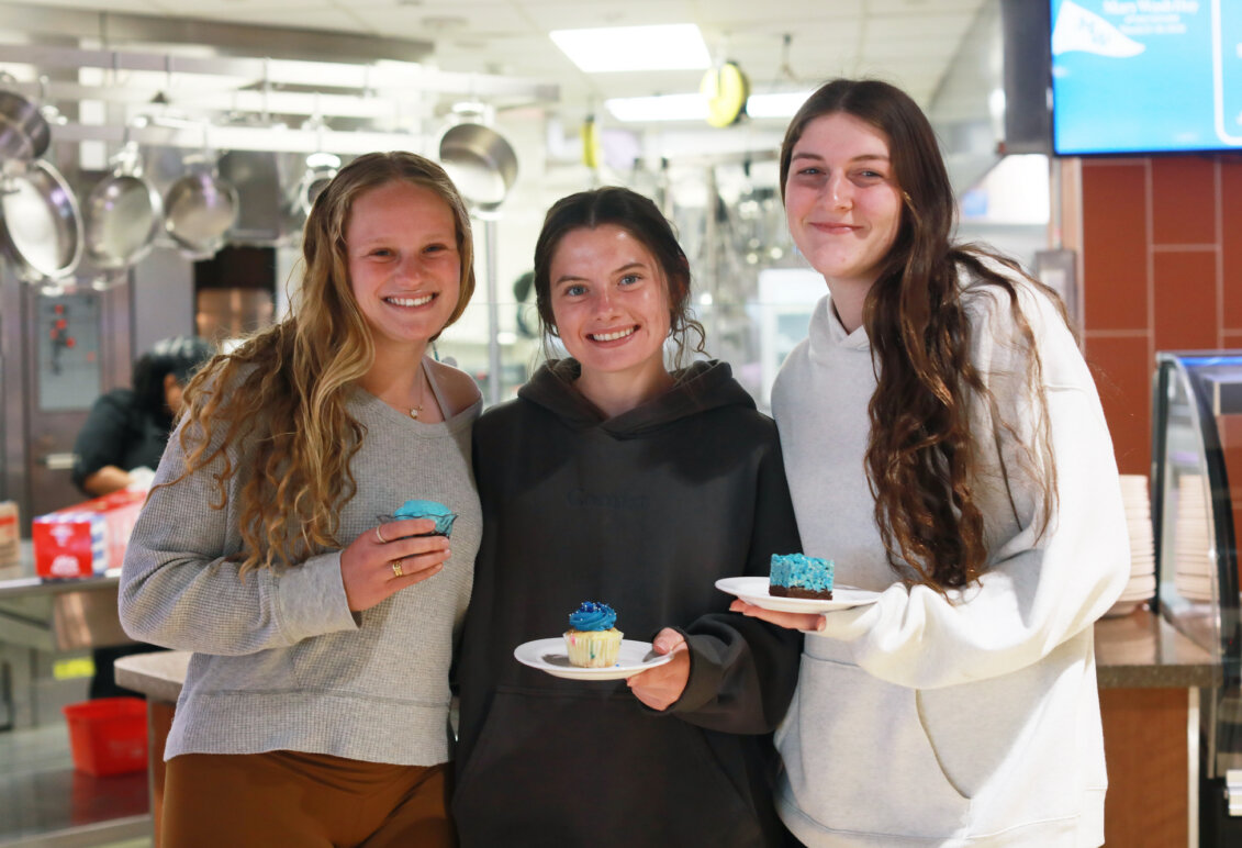 Three students in the UMW Dining facility holding blue desserts.