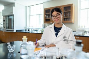 Photo of Ashley Lam in a lab coat in a UMW science classroom