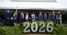 Several people stand in a row looking at the camera and dressed in graduation garb with the number "2026" in front of them