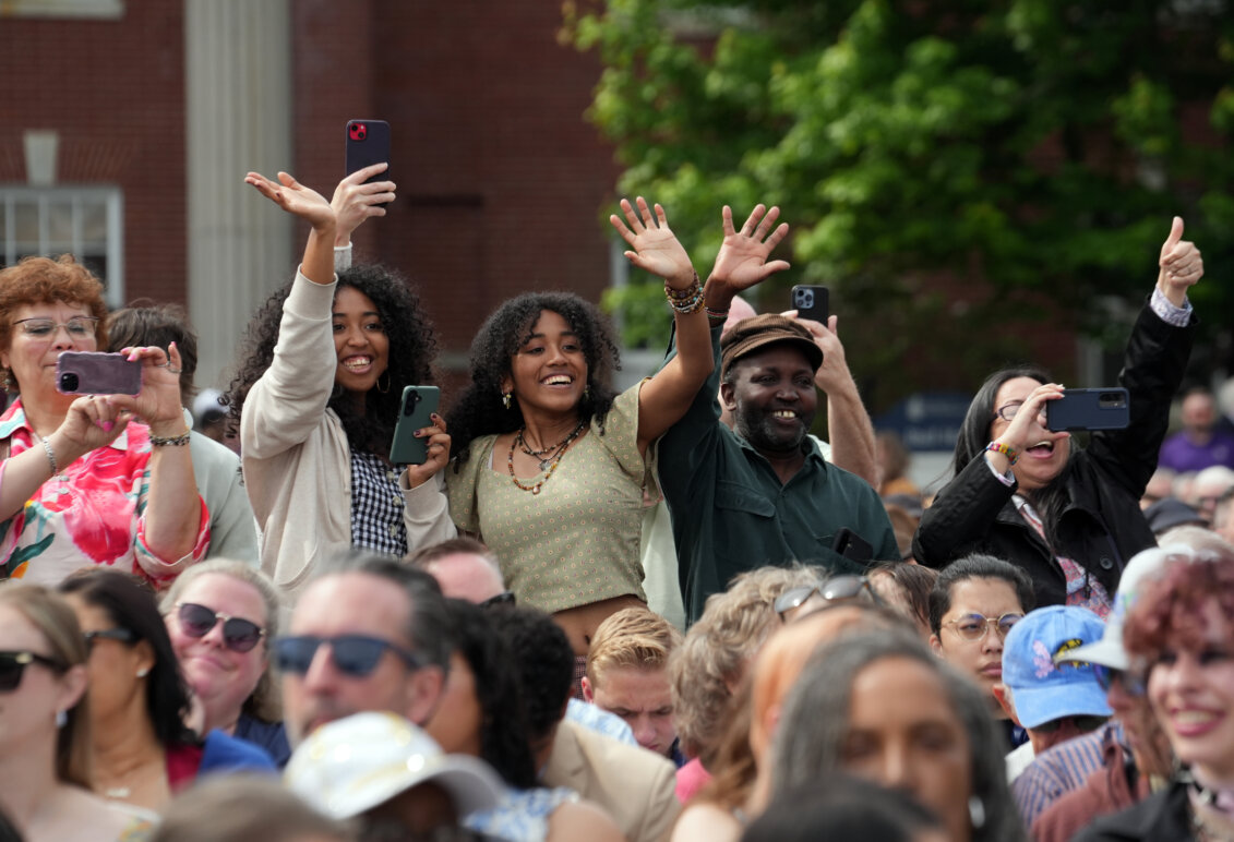 A group of people wave and take photos