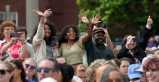 A group of people wave and take photos