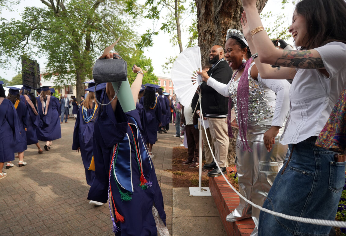 People clap as soon-to-be graduates pass by