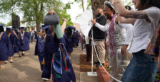 People clap as soon-to-be graduates pass by