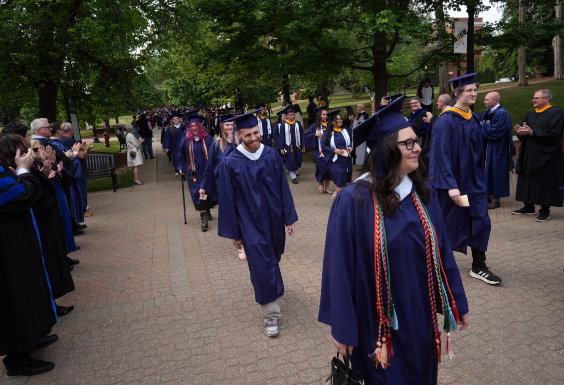 Students dressed in graduation garb process toward the ceremony