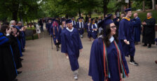 Students dressed in graduation garb process toward the ceremony