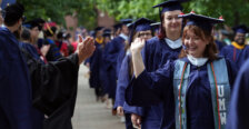 People dressed in graduation garb prepare to give each other a high-five
