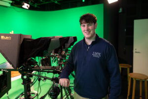 Matthew Clinton stands next to a camera in a production studio