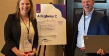 Marty Bywaters-Baldwin poses with a female colleague next to a sign advertising his session at a statewide symposium