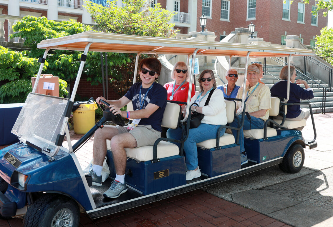 A student-led golf cart tour of campus stops in front of Lee Hall.