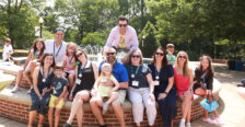 Alumni with their kids, several of whom have painted faces, seated at the fountain in front of Monroe Hall during Reunion Weekend.