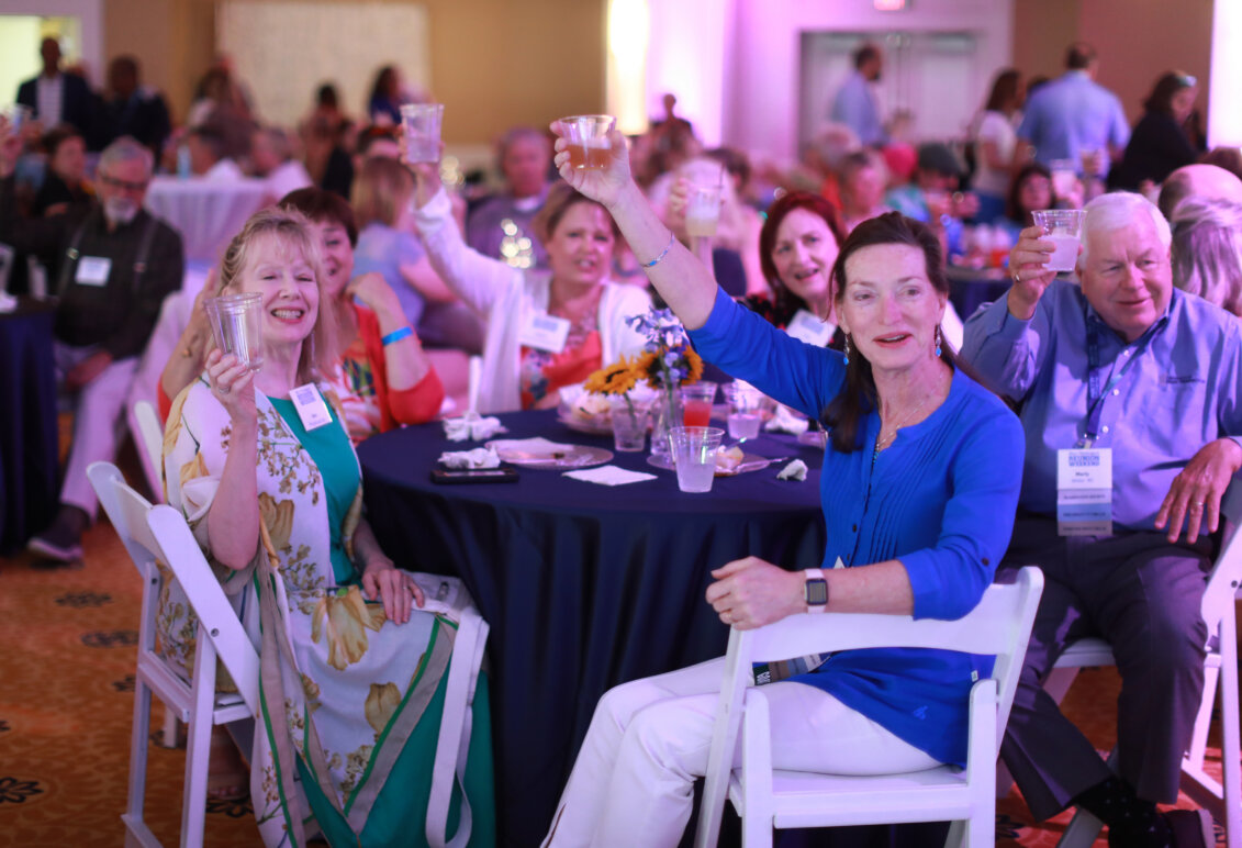 A group of alumni raise their glasses in a toast while seated a table at the all-class party during Reunion Weekend.