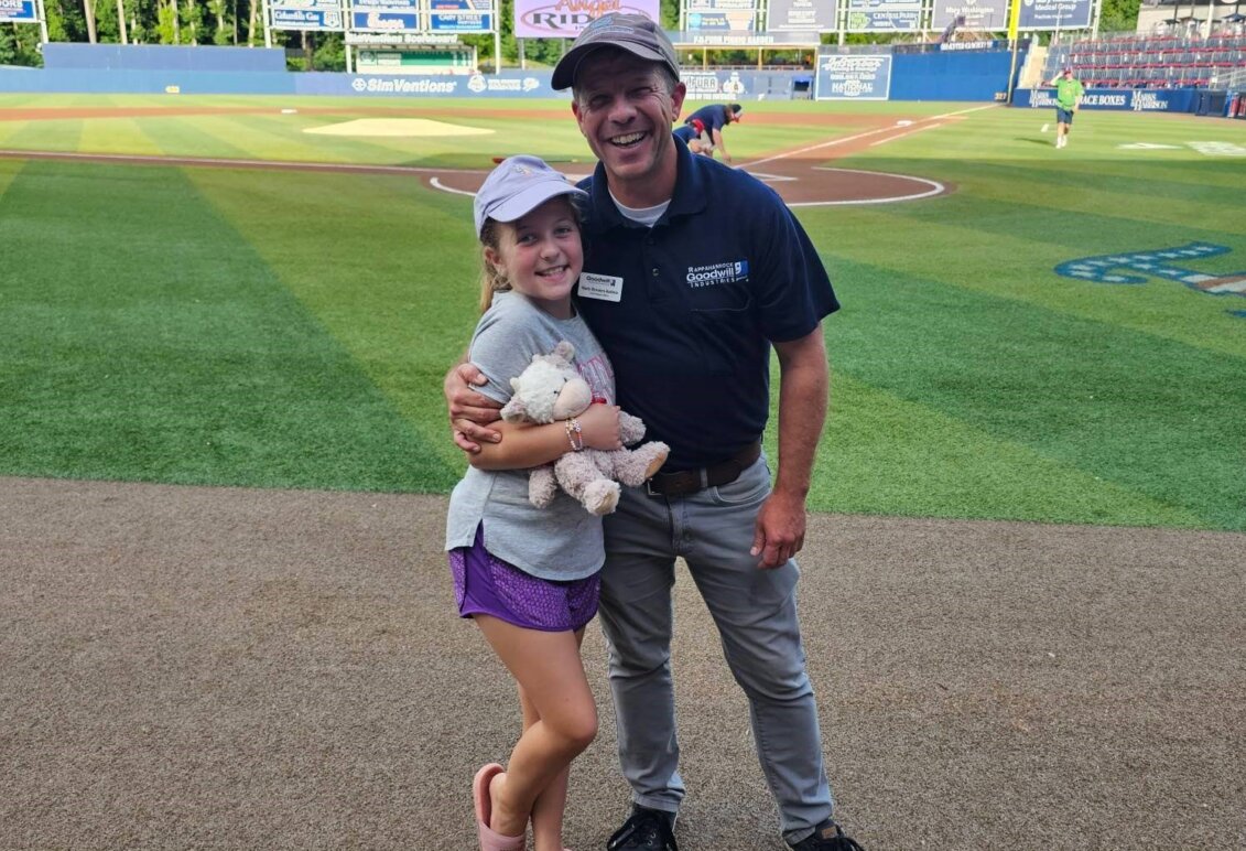 Marty Bywaters-Baldwin stands with daughter at a Fred Nats game