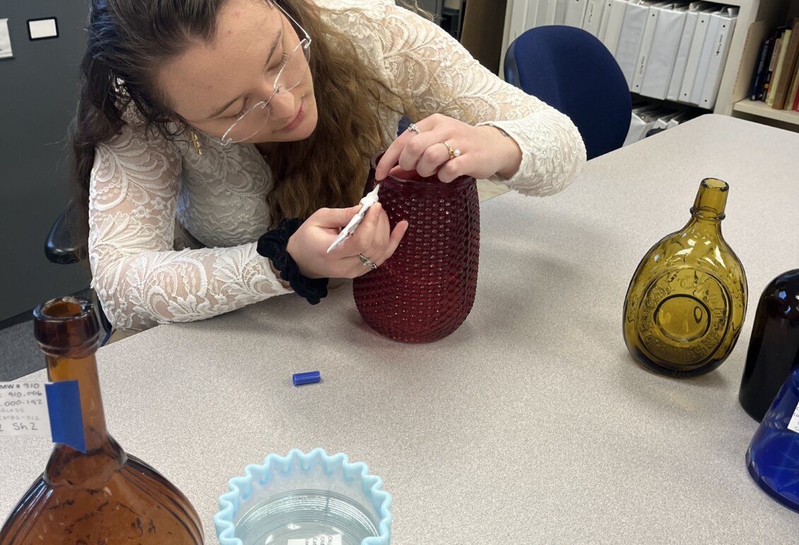 Bowman works at a table cross mending glass in an office