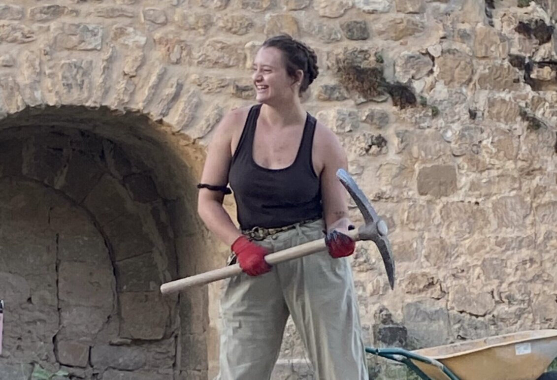 Bowman holding a pick ax on an excavation in Spain