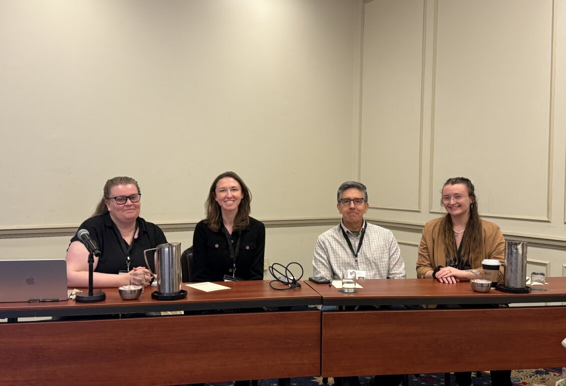 Bowman and three other panelists pose for a photo while sitting at a table