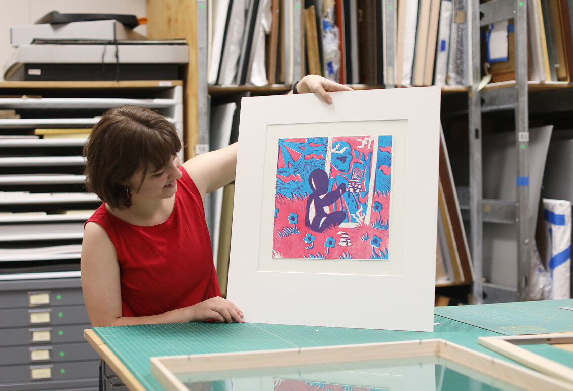 A student holds up a piece of art.