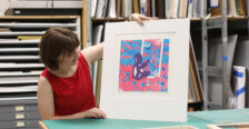 A student holds up a piece of art.