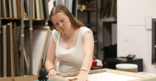 A student works on framing a painting inside an art gallery.