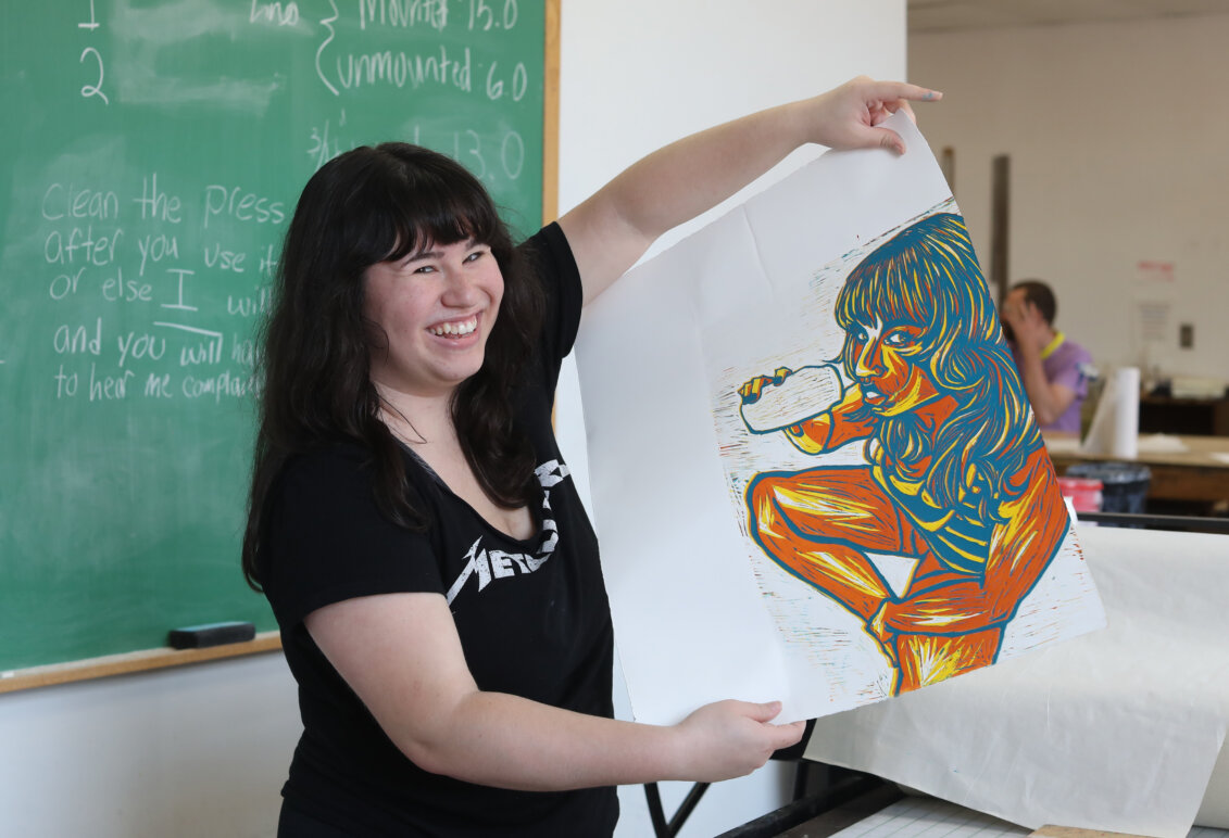 A student holds up a piece of artwork.