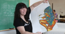 A student holds up a piece of artwork.
