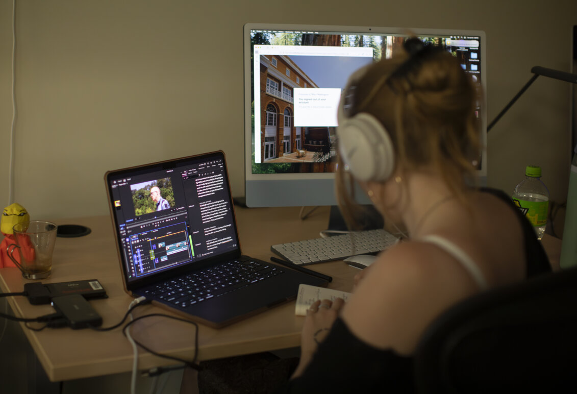 A student wearing headphones works on a laptop.