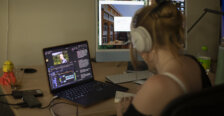 A student wearing headphones works on a laptop.