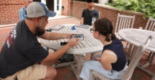 A Rappahannock River expert shows an iPhone photo to a UMW student, while another student and a professor look on.