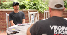 A student sits across an outside table from a man.