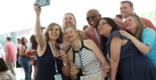 A group of 1990s alumni take a selfie while holding wine glasses.