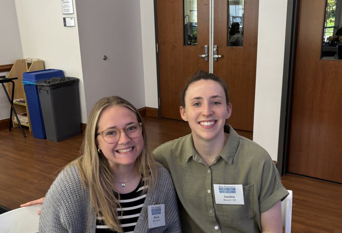 Brianna Burckhalter seated with award winner, Carolina Brusch '23 at COB Alumni Awards event