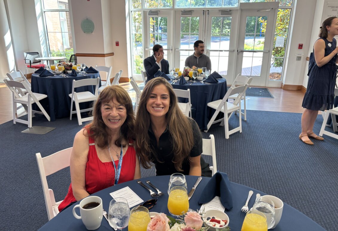 Christina Malave at a table in Woodard Hall with a guest at the Alumni Awards event.