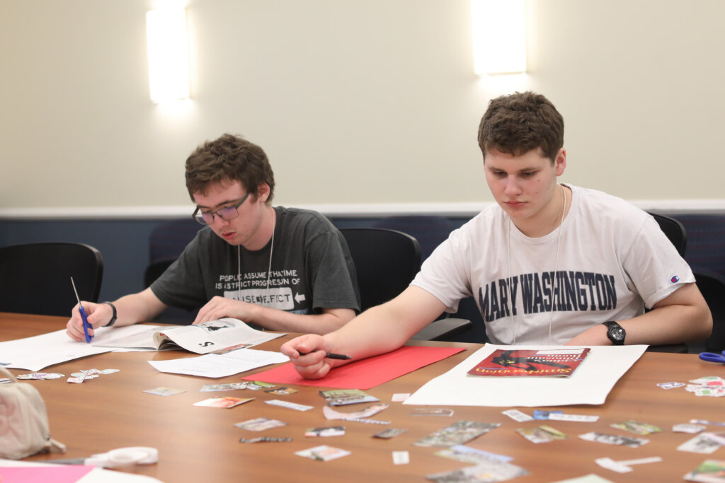 Two guys sit at a table looking through magazines and building vision boards that represent themselves and their futures