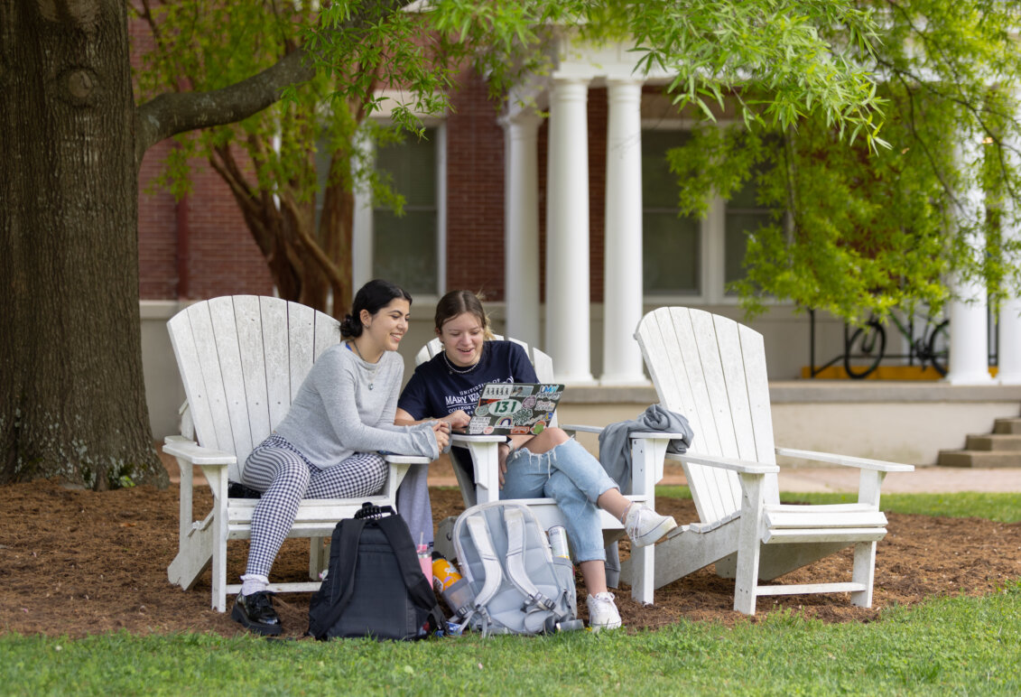 Two students sit in chairs on Ball Circle on UMW campus grounds