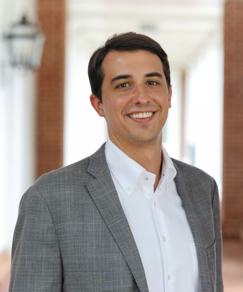 A man wearing a suit smiles at the camera