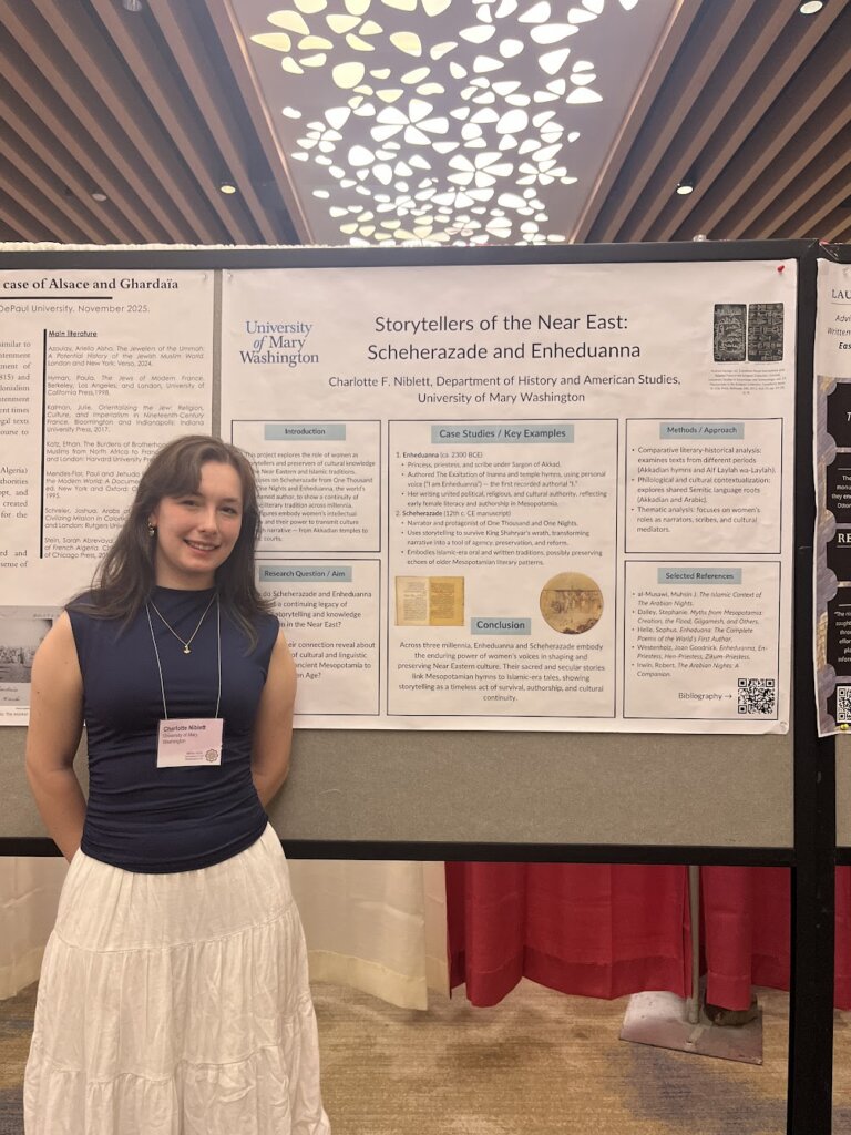 A young woman stands in front of academic posters as she presents at a conference