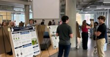 Students stand in front of posters to explain their findings